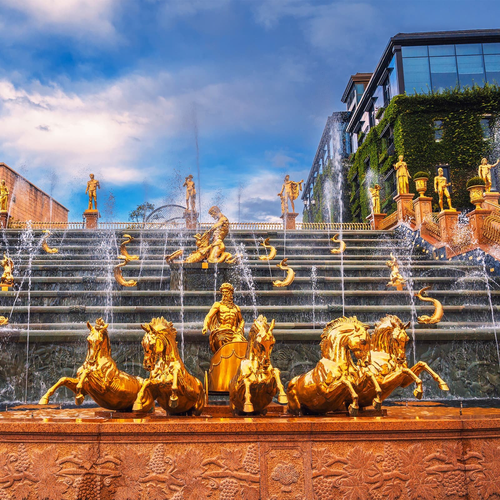 Скульптурный водопад Helios в Ba Na Hills — место, где туристы отдыхают между аттракционами, любуясь каскадами воды и панорамами гор на заднем плане.