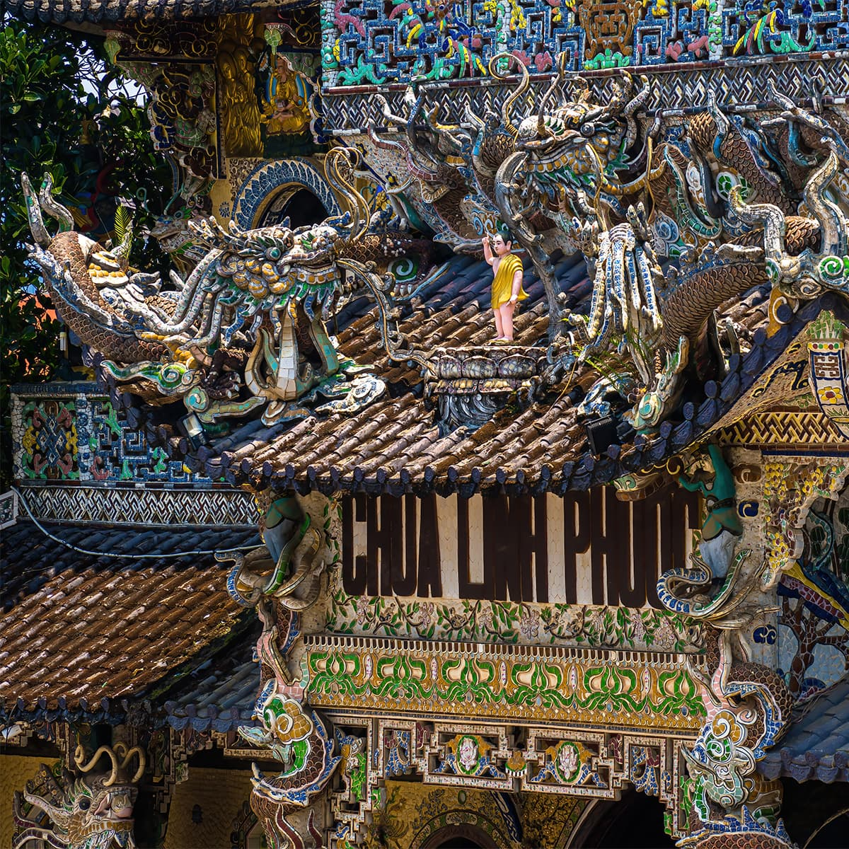 Главный зал пагоды Линь Фуок снаружи: над входом мозаичные драконы и узоры из осколков керамики — тот самый фантастический стиль, который принёс храму прозвище «бутылочная пагода».