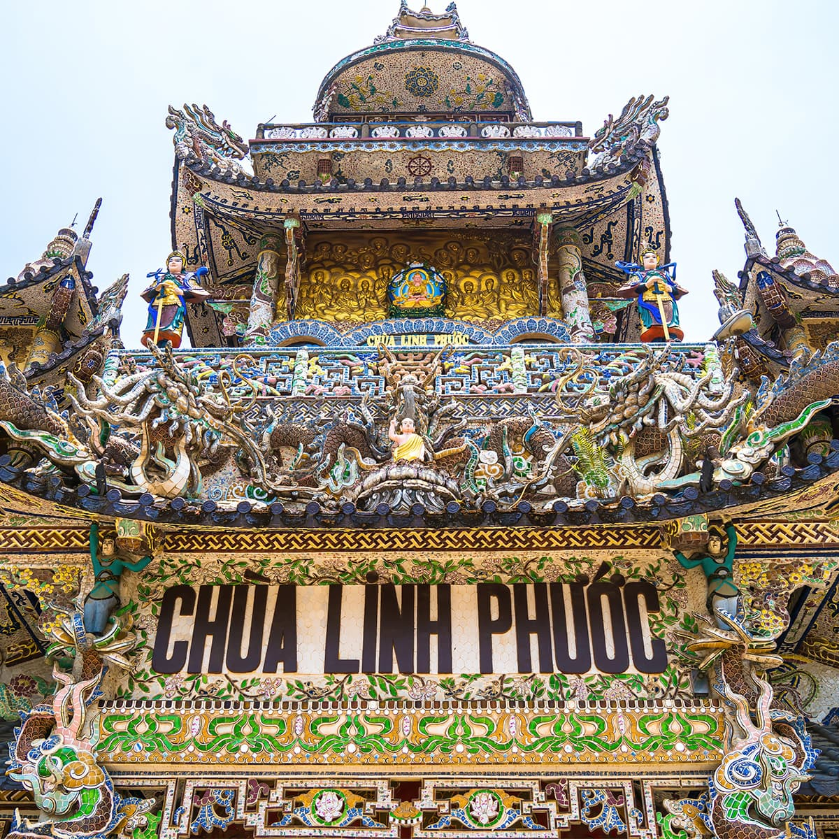 Фасад Chánh điện пагоды Линь Фуок: архитектурные элементы над входом собраны как мозаичный барельеф, превращая храм в художественный лабиринт Траймата.