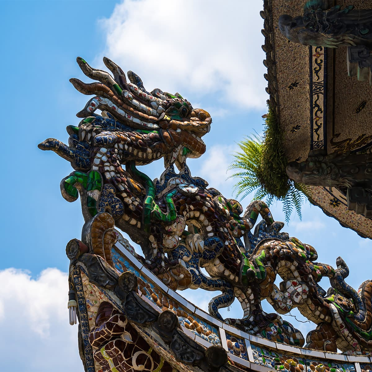 Дракон-элемент каскада башни Tháp Đa Bảo в Линь Фуок: мозаичная чешуя и изгибы словно оживают на солнце, продолжая «драконью» тему всего комплекса.
