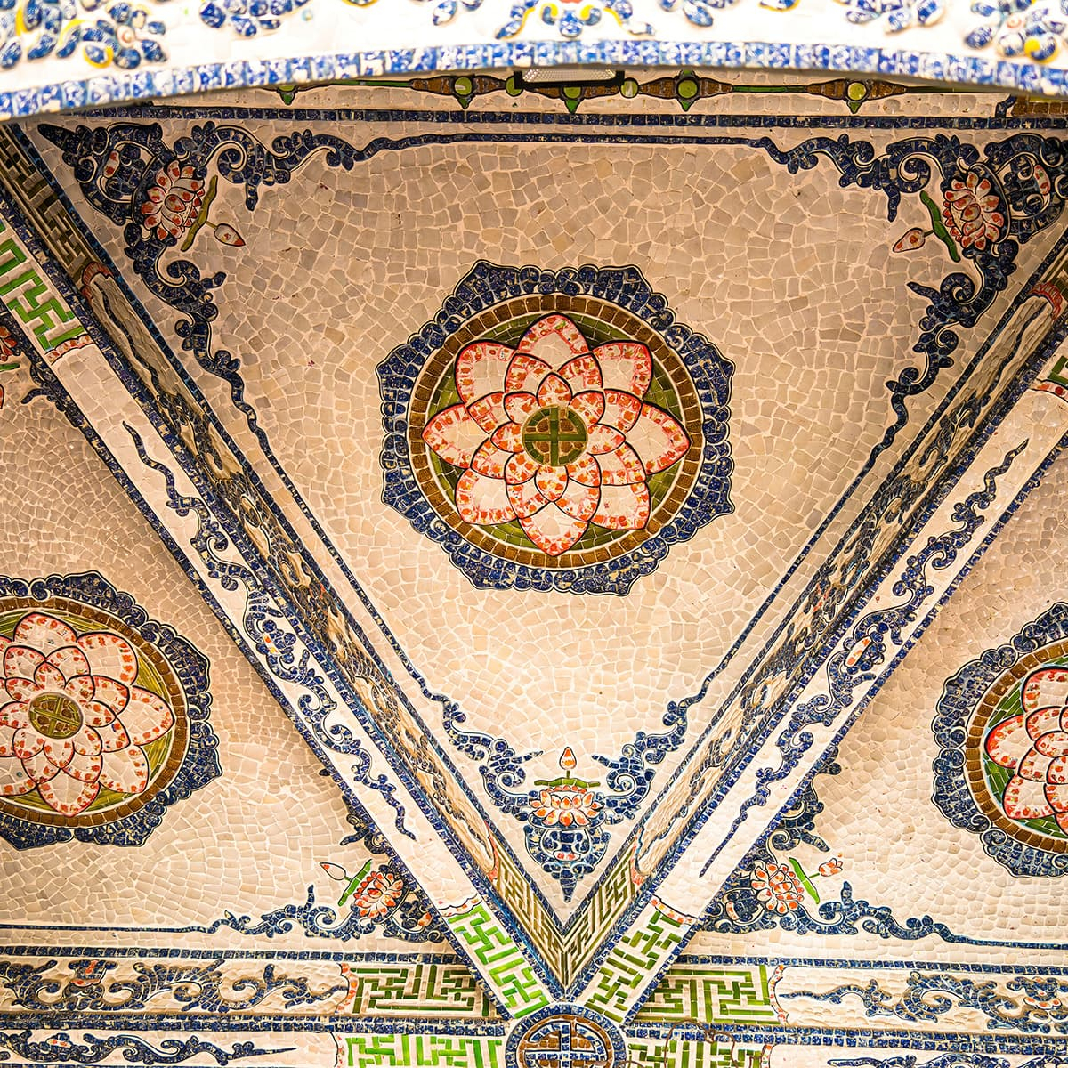 Традиционная буддийская символика в Линь Фуок соединяется с декоративной фантазией мастеров: драконы, облака и орнаменты собраны вручную из тысяч стеклянных фрагментов.