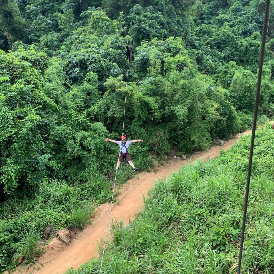 Турист проходит спуск на зиплайне, скользя над зелёными уровнями леса и наблюдая, как тропы исчезают под плотной листвой