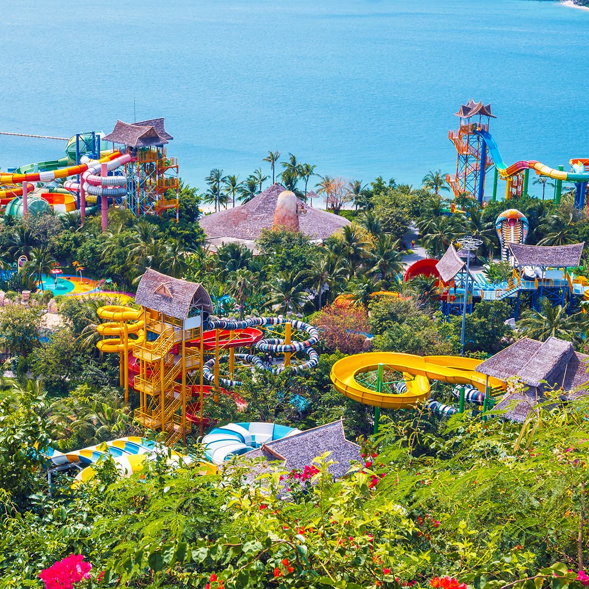 Панорама разноцветных водных горок Tropical Paradise среди пальм у моря в парке VinWonders Nha Trang