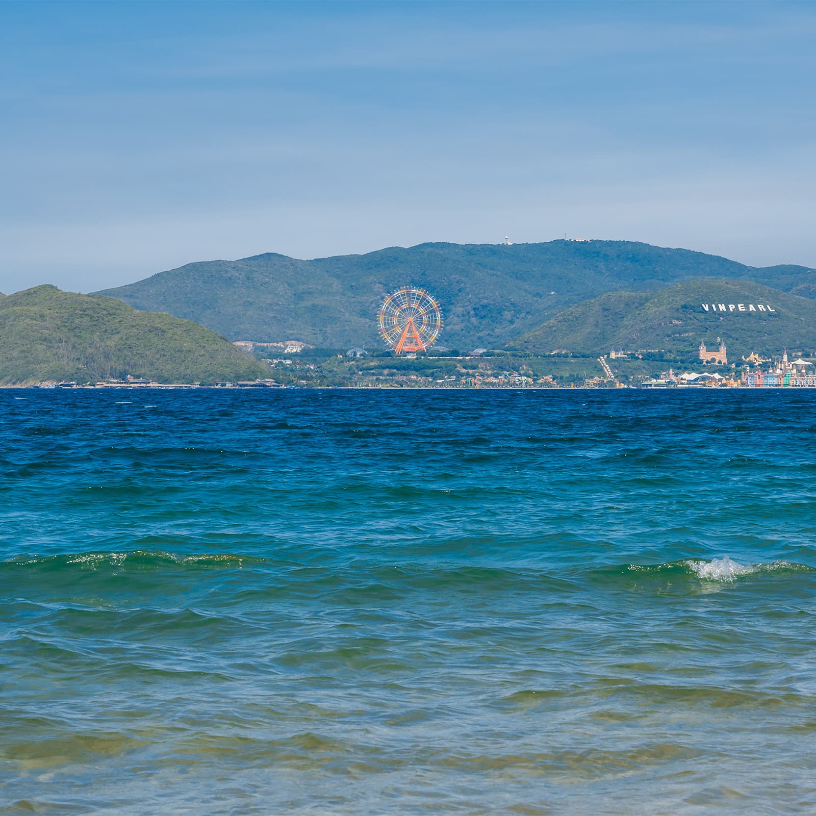 Панорама острова Хонче с моря: колесо Sky Wheel и надпись Vinpearl на склоне над парком Винвандерс Нячанг